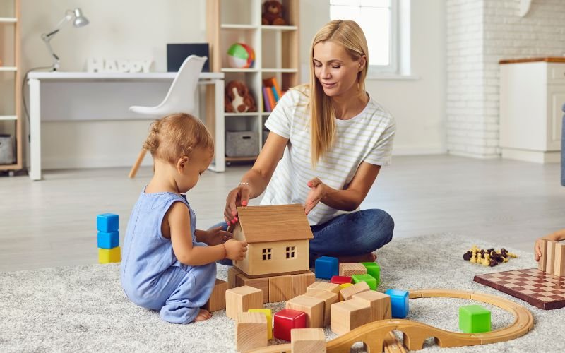 mother and baby girl building together with toys